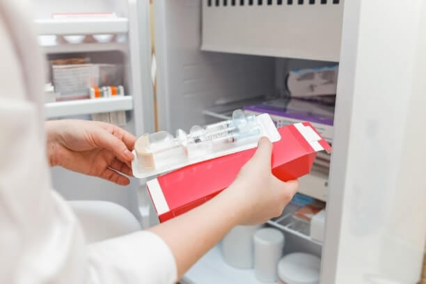 lab technician taking product out of medical refrigerator